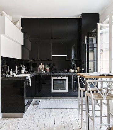 Bucătărie neagră și pat deasupra intrării într-o garsonieră de 37 m²